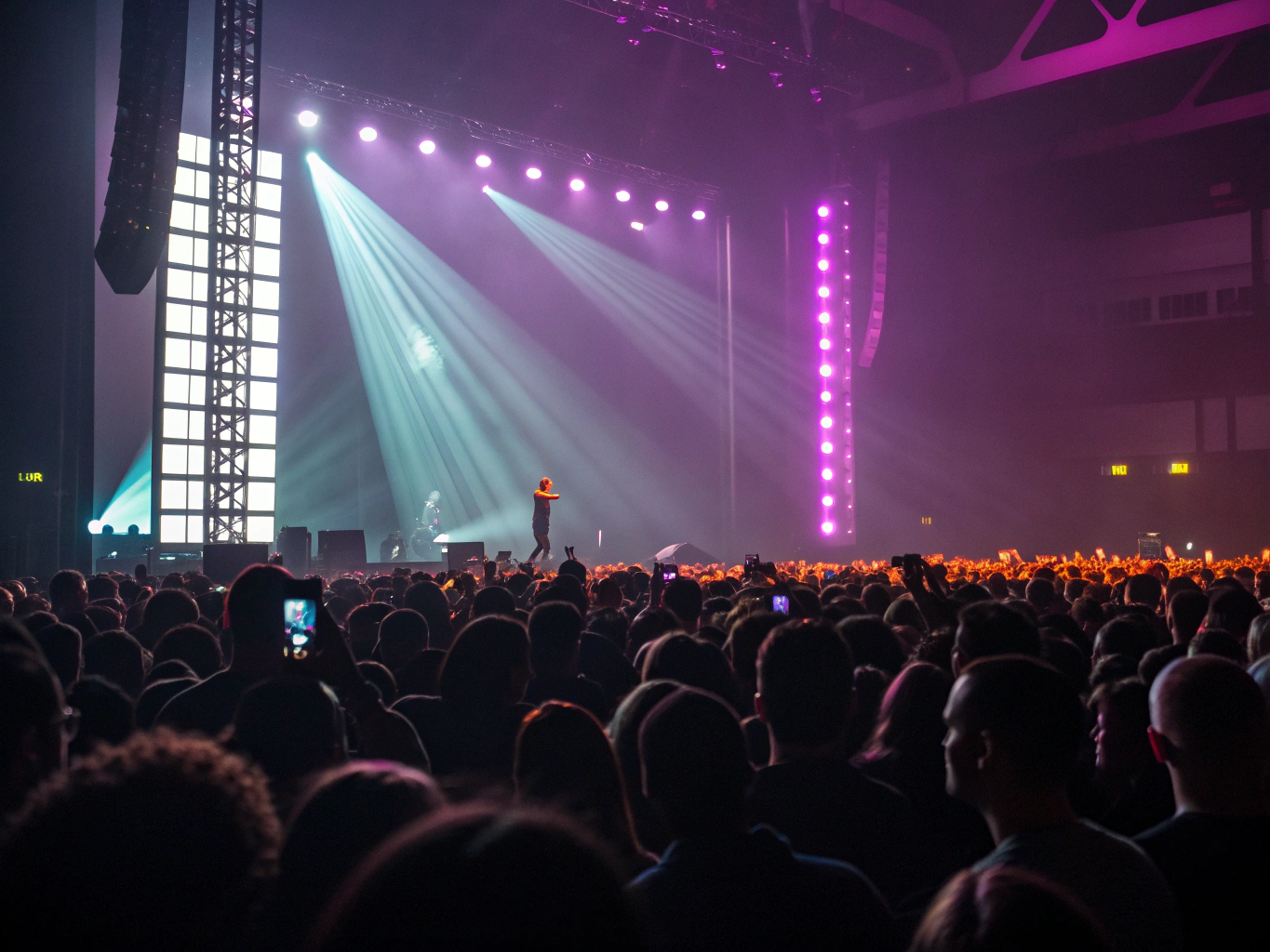 View of roaring stadium crowd illuminated by lasers from side stage monitor console